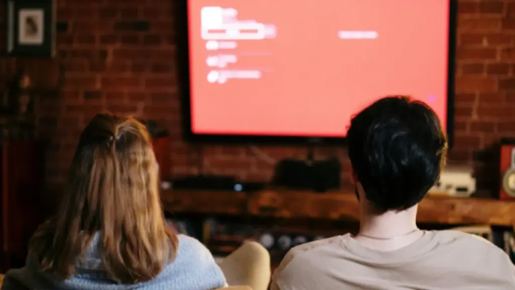 Casal sentado no sofá assistindo televisão juntos, representando momentos de entretenimento em casa